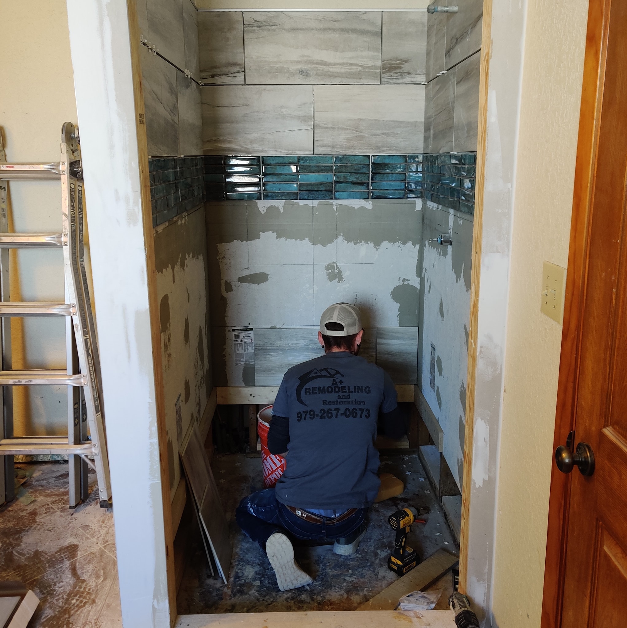 A+ Remodeling and Restoration contractor installing shower tile on a job site
